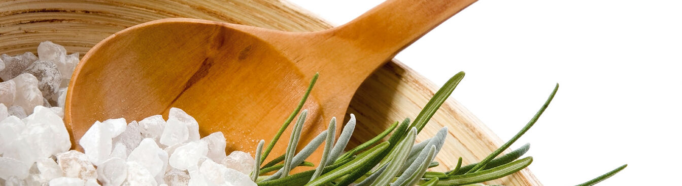 Holzschale mit grobem Salz, einem Holzlöffel und einem Rosmarinzweig. Weiße Hintergrund betont die natürlichen Elemente. Holzschale mit grobem Salz, einem Holzlöffel und einem Rosmarinzweig. Weiße Hintergrund betont die natürlichen Elemente.