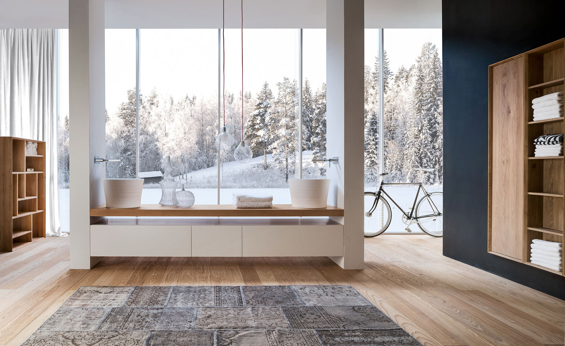 Geräumiges, modernes Badezimmer mit Holzfußboden, freistehenden Waschbecken, großen Fenstern mit Blick auf verschneite Landschaft und dekorativem Teppich. Geräumiges, modernes Badezimmer mit Holzfußboden, freistehenden Waschbecken, großen Fenstern mit Blick auf verschneite Landschaft und dekorativem Teppich.