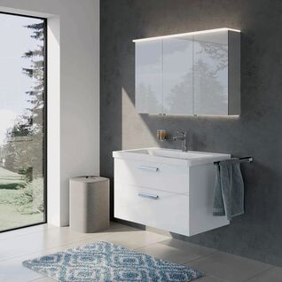 Modernes Badezimmer mit schwebendem wei&szlig;en Waschtisch und beleuchtetem Spiegelschrank. Eine gro&szlig;e Fensterfront sorgt f&uuml;r viel nat&uuml;rliches Licht. Ein blauer Teppich erg&auml;nzt das Design.