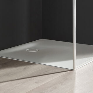 Ecke einer modernen Duschkabine mit klaren Glaswänden und einer weißen Duschwanne. Der Boden besteht aus hellem Holz, daneben ein Korb mit Handtüchern. Ecke einer modernen Duschkabine mit klaren Glaswänden und einer weißen Duschwanne. Der Boden besteht aus hellem Holz, daneben ein Korb mit Handtüchern.