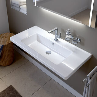 Modernes Badezimmer mit weißem Waschbecken, Spiegel, Seifenspender, Becherhalter, Handtuchhalter an der Wand und Korb in der Ecke. Modernes Badezimmer mit weißem Waschbecken, Spiegel, Seifenspender, Becherhalter, Handtuchhalter an der Wand und Korb in der Ecke.