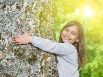 Das Bild zeigt ein Kind, das einen Baum umarmt. Dies symbolisiert eine Verbindung zur Natur und Freude an der Umwelt. Das Bild zeigt ein Kind, das einen Baum umarmt. Dies symbolisiert eine Verbindung zur Natur und Freude an der Umwelt.