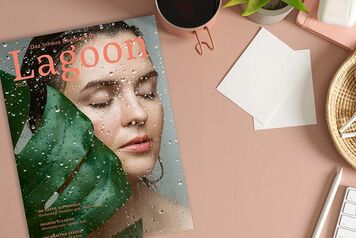 Magazin "Lagoon" mit Bild einer Person hinter Blatt, daneben Laptop, Kopfhörer, Tasse und Notizzettel auf Tisch. Magazin "Lagoon" mit Bild einer Person hinter Blatt, daneben Laptop, Kopfhörer, Tasse und Notizzettel auf Tisch.
