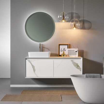 Modernes Badezimmer mit rundem, beleuchtetem Spiegel, hängendem Waschtisch und freistehender Badewanne. Graue Wände, stilvolle Beleuchtung, minimalistische Dekoration. Modernes Badezimmer mit rundem, beleuchtetem Spiegel, hängendem Waschtisch und freistehender Badewanne. Graue Wände, stilvolle Beleuchtung, minimalistische Dekoration.