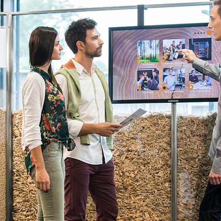 Drei Personen stehen vor einem Bildschirm und diskutieren über Bilder und Informationen, die darauf angezeigt werden. Drei Personen stehen vor einem Bildschirm und diskutieren über Bilder und Informationen, die darauf angezeigt werden.