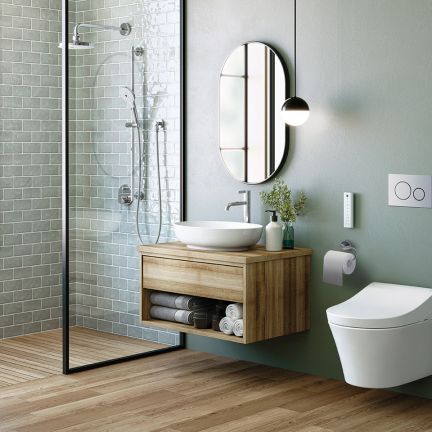 Ein modernes Badezimmer mit einer offenen Dusche, grünen Wänden und einem hängenden Waschtisch aus Holz. Ein ovaler Spiegel und eine schwebende Toilette ergänzen das Design.
