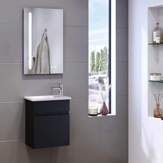 Badezimmer mit einem schwebenden schwarzen Waschtisch und einem beleuchteten Spiegel. Große graue Fliesen und ein schmaler Fensterschlitz lassen viel Licht herein. Badezimmer mit einem schwebenden schwarzen Waschtisch und einem beleuchteten Spiegel. Große graue Fliesen und ein schmaler Fensterschlitz lassen viel Licht herein.