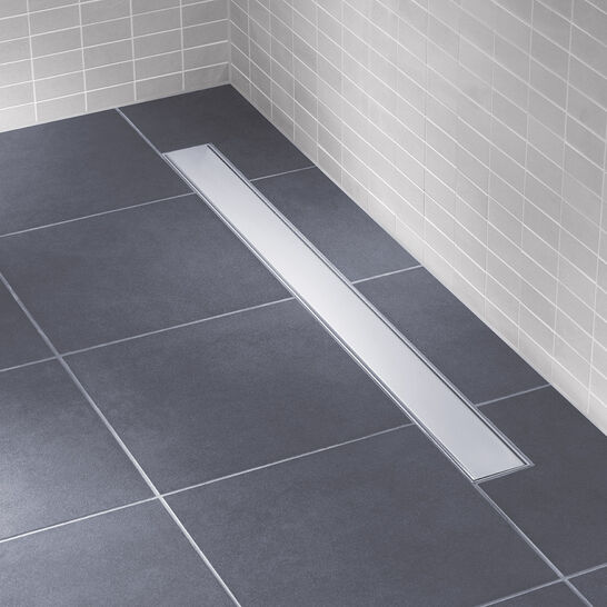 Bodengleiche Dusche mit dunklen Fliesen und einer modernen, schmalen Ablaufrinne. Helle Wandfliesen sorgen für einen klaren, minimalistischen Look. Bodengleiche Dusche mit dunklen Fliesen und einer modernen, schmalen Ablaufrinne. Helle Wandfliesen sorgen für einen klaren, minimalistischen Look.