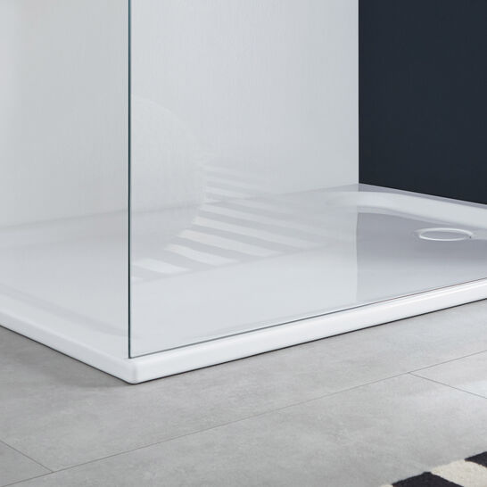 Moderne Dusche mit klaren Glaswänden und einer flachen, weißen Duschwanne. Der Boden ist mit grauen Fliesen bedeckt, daneben ein Korb mit einem Handtuch und ein Teppich. Moderne Dusche mit klaren Glaswänden und einer flachen, weißen Duschwanne. Der Boden ist mit grauen Fliesen bedeckt, daneben ein Korb mit einem Handtuch und ein Teppich.