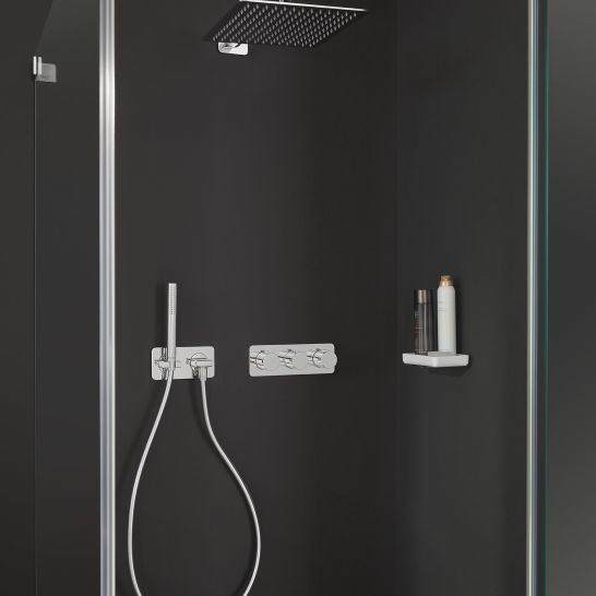 Moderne, elegante Dusche mit dunklen W&auml;nden. Quadratische Regendusche und Handbrause mit silbernen Armaturen. Einfache Ablage f&uuml;r Duschutensilien.