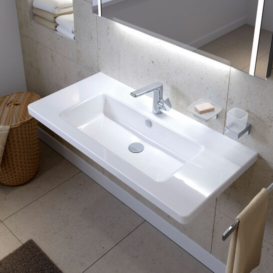Ein modernes Badezimmer mit einem weißen Waschbecken, einem Spiegel darüber, einem Wasserhahn, Seifenhalter und einem Handtuchhalter an der Seite. Ein modernes Badezimmer mit einem weißen Waschbecken, einem Spiegel darüber, einem Wasserhahn, Seifenhalter und einem Handtuchhalter an der Seite.