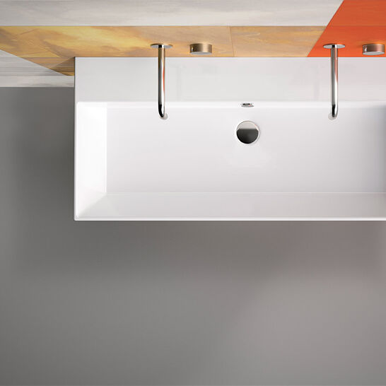 Modernes, rechteckiges Waschbecken mit minimalistischer Form. Befestigung an einer farblich gestalteten Wand mit Grautönen und Akzenten in Orange und Gelb. Modernes, rechteckiges Waschbecken mit minimalistischer Form. Befestigung an einer farblich gestalteten Wand mit Grautönen und Akzenten in Orange und Gelb.