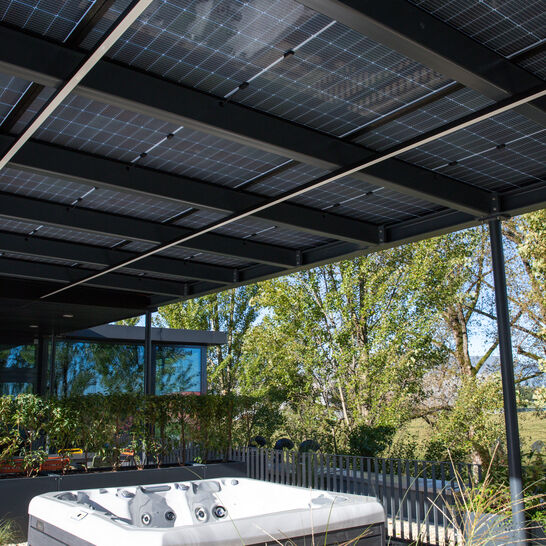Ein moderner Außenbereich mit einem Whirlpool. Überdacht von Solarpanelen. Umgeben von Pflanzen und Bäumen, vermittelt er eine entspannende Atmosphäre Ein moderner Außenbereich mit einem Whirlpool. Überdacht von Solarpanelen. Umgeben von Pflanzen und Bäumen, vermittelt er eine entspannende Atmosphäre
