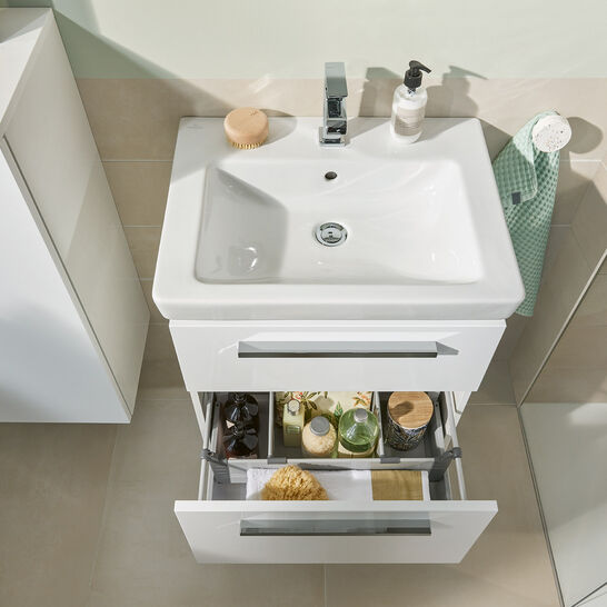 Weißes Badezimmerwaschbecken mit Stauraum darunter. Geöffnete Schublade zeigt organisierte Pflegeprodukte. Modern, hell und funktional gestaltet. Weißes Badezimmerwaschbecken mit Stauraum darunter. Geöffnete Schublade zeigt organisierte Pflegeprodukte. Modern, hell und funktional gestaltet.