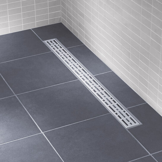 Bodengleiche Dusche mit dunklen Fliesen und einer modernen, schmalen Ablaufrinne mit perforiertem Design. Helle Wandfliesen für einen minimalistischen Look. Bodengleiche Dusche mit dunklen Fliesen und einer modernen, schmalen Ablaufrinne mit perforiertem Design. Helle Wandfliesen für einen minimalistischen Look.