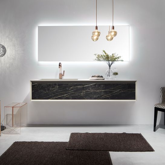 Modernes Badezimmer mit beleuchtetem Spiegel, h&auml;ngendem Waschtisch in Marmoroptik, eleganter Beleuchtung und stilvollen Accessoires. Gem&uuml;tlich und schick.