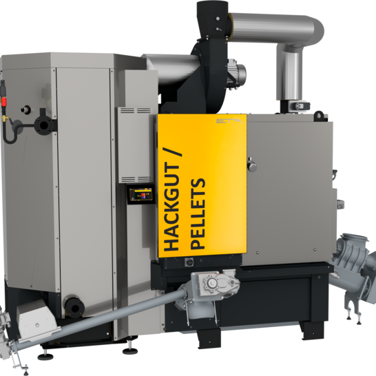 Das Bild zeigt einen Hackgut-/Pelletkessel. Er ist mit einem gelben Schild gekennzeichnet und verfügt über Rohre und Mechanismen für die Brennstoffzufuhr. Hackschnitzelanlage von ETA