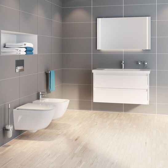 Badezimmer mit grauen Fliesen, wandhängendem WC und Bidet. Weißer Waschtisch mit Spiegel, eingebautes Regal, helle Holzbodenoptik. Badezimmer mit grauen Fliesen, wandhängendem WC und Bidet. Weißer Waschtisch mit Spiegel, eingebautes Regal, helle Holzbodenoptik.