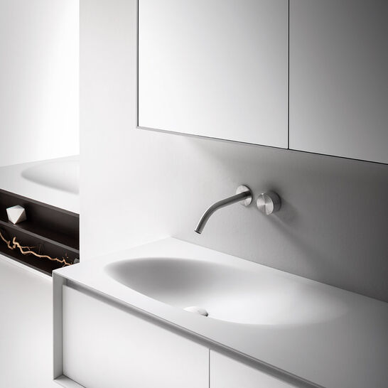 Modernes Badezimmer mit minimalistischem Design. Weißer Waschtisch, wandmontierter Wasserhahn und Spiegelschrank. Dezente, klare Linien. Modernes Badezimmer mit minimalistischem Design. Weißer Waschtisch, wandmontierter Wasserhahn und Spiegelschrank. Dezente, klare Linien.