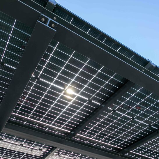 Ein Solardach mit mehreren Solarpaneelen, die in einem Metallrahmen angebracht sind. Die Sonne scheint durch die Paneele, und der Himmel ist klar und blau. Ein Solardach mit mehreren Solarpaneelen, die in einem Metallrahmen angebracht sind. Die Sonne scheint durch die Paneele, und der Himmel ist klar und blau.