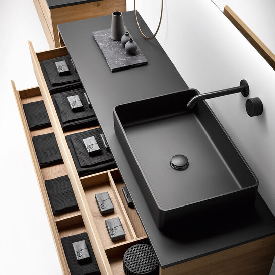 Badezimmer mit schwarzem Waschtisch, offenen Holzschubladen, organisierten Fächern und minimalistischem Design. Badezimmer mit schwarzem Waschtisch, offenen Holzschubladen, organisierten Fächern und minimalistischem Design.