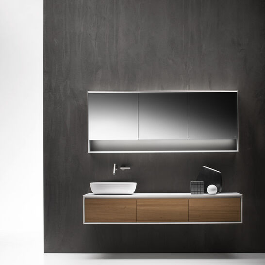 Modernes Badezimmer mit dunkler Wand, schwebendem Holzunterschrank, weißem Aufsatzwaschbecken und beleuchtetem Spiegel. Minimalistisches Design. Modernes Badezimmer mit dunkler Wand, schwebendem Holzunterschrank, weißem Aufsatzwaschbecken und beleuchtetem Spiegel. Minimalistisches Design.