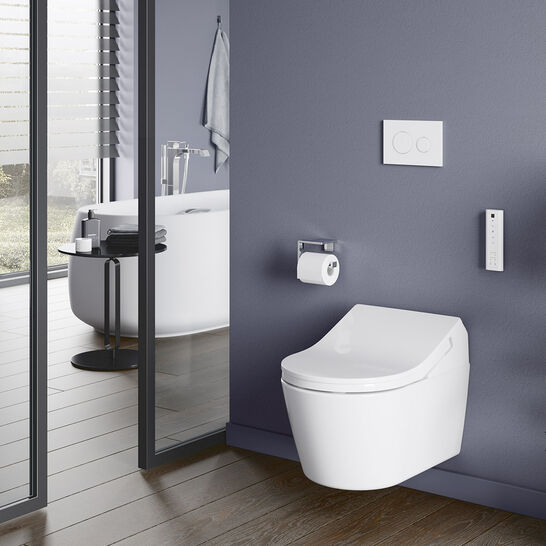 Modernes Badezimmer mit lila Wand, wandhängendem WC und integriertem Bedienfeld. Holzfußboden, angrenzender Raum mit freistehender Badewanne, große Fensterfronten mit viel natürlichem Licht. Modernes Badezimmer mit lila Wand, wandhängendem WC und integriertem Bedienfeld. Holzfußboden, angrenzender Raum mit freistehender Badewanne, große Fensterfronten mit viel natürlichem Licht.