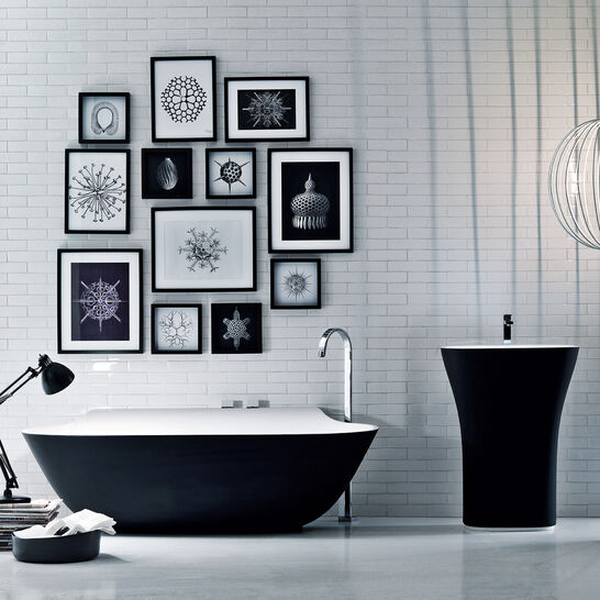 Badezimmer mit schwarzer Badewanne und passendem Waschbecken. Kunstvolle Bilder an der Wand und eine stilvolle Hängelampe schaffen ein elegantes Ambiente. Badezimmer mit schwarzer Badewanne und passendem Waschbecken. Kunstvolle Bilder an der Wand und eine stilvolle Hängelampe schaffen ein elegantes Ambiente.