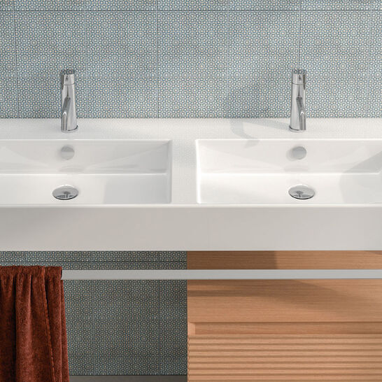 Modernes Doppelwaschbecken mit schlichten Armaturen und Handtuchhalter. Dezenter blauer Fliesenhintergrund, erg&auml;nzt durch Dekor und Holzdetails.