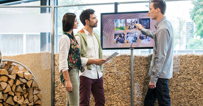 Drei Personen stehen vor einem Bildschirm und diskutieren über Bilder und Informationen, die darauf angezeigt werden. Drei Personen stehen vor einem Bildschirm und diskutieren über Bilder und Informationen, die darauf angezeigt werden.